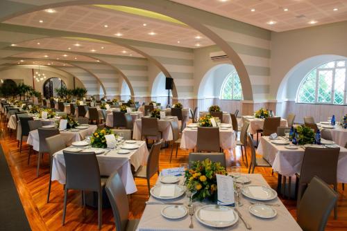 um grande salão de banquetes com mesas e cadeiras brancas em Grand Resort Serra Negra em Serra Negra