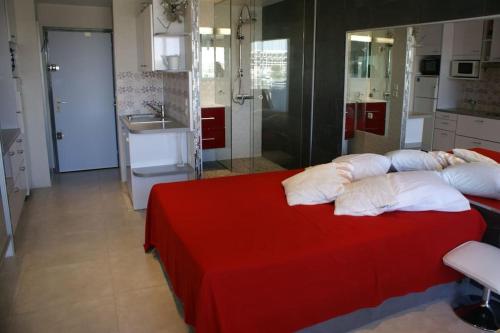 - une chambre avec un lit rouge et des oreillers blancs dans l'établissement Studio 309, Héliopolis AB, village naturiste, au Cap d'Agde