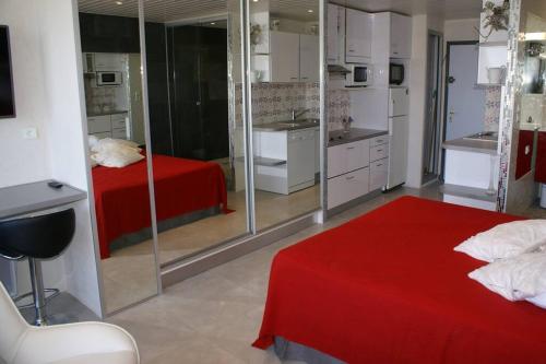 Cet appartement comprend une chambre avec un lit rouge et une cuisine. dans l'établissement Studio 309, Héliopolis AB, village naturiste, au Cap d'Agde
