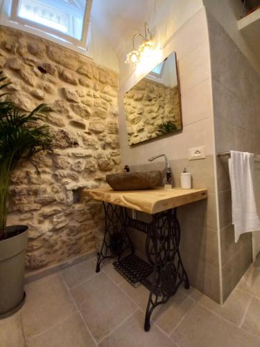 La salle de bains est pourvue d'un lavabo et d'un mur en pierre. dans l'établissement Casa Pupi, à Noto