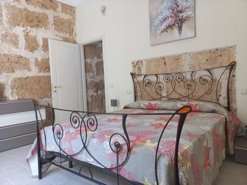 Ce lit se trouve dans un dortoir doté d'un mur en pierre. dans l'établissement Casa Pupi, à Noto
