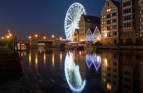 a reflection of a city at night with boats in the water at Podewils Old Town Gdansk in Gdańsk