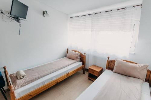 a bedroom with two beds and a tv and a window at Palma Vendégház in Szeged