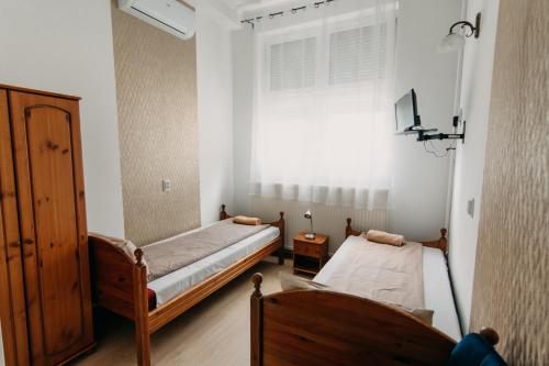 two beds in a room with a window at Palma Vendégház in Szeged