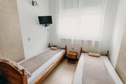 two beds in a small room with a window at Palma Vendégház in Szeged