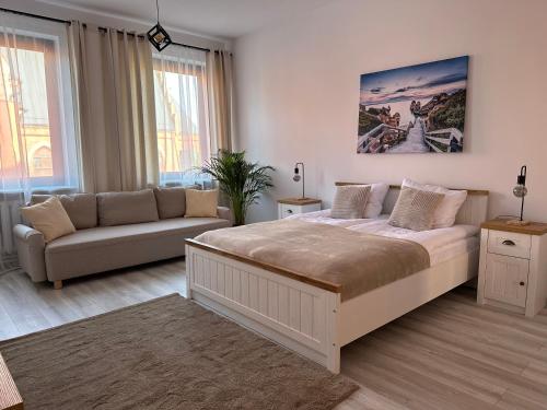 a bedroom with a large bed and a couch at Apartamenty Przy Deptaku in Świnoujście