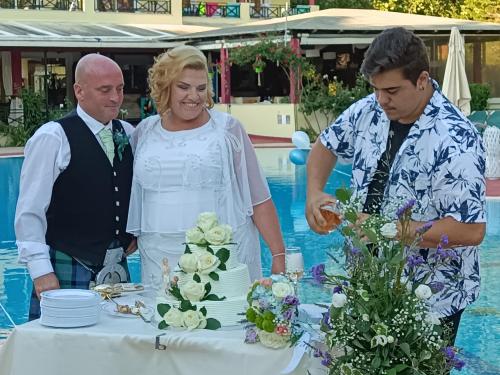 Un uomo e una donna in piedi accanto a un tavolo con una torta di DAMIA HOTEL Apts a Sidari