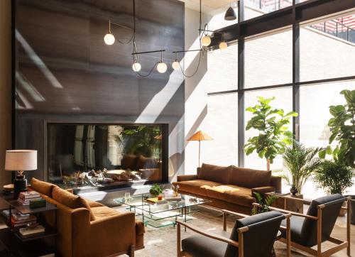 a living room with leather furniture and a large window at Roost Baltimore in Baltimore