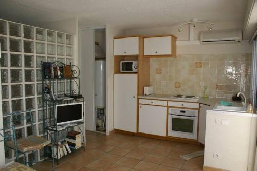 une cuisine avec des armoires blanches et un four à plaques de cuisson dans l'établissement Villa 34, Port Nature Village, Quartier naturiste, au Cap d'Agde