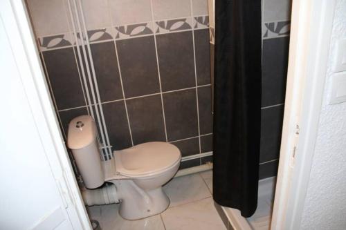 La salle de bains est pourvue de toilettes et d'un rideau de douche noir. dans l'établissement Studio 82, Héliopolis FGH au Village naturiste, au Cap d'Agde