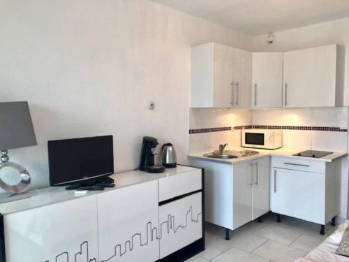 une cuisine blanche avec des armoires blanches et un micro-ondes dans l'établissement Studio 82, Héliopolis FGH au Village naturiste, au Cap d'Agde