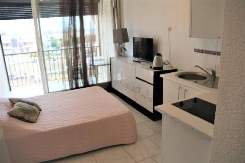 Il comprend une chambre avec un lit et une cuisine avec un évier. dans l'établissement Studio 82, Héliopolis FGH au Village naturiste, au Cap d'Agde