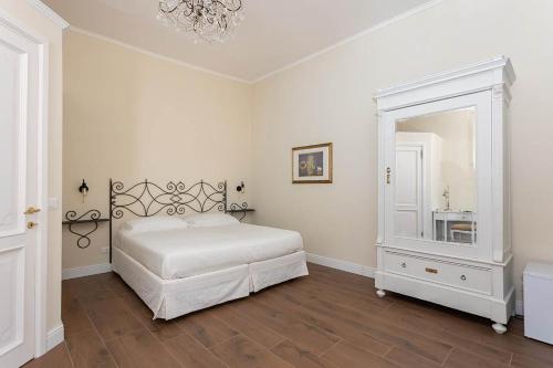 a white bedroom with a bed and a mirror at Borgo Prima Luce in Cuglieri