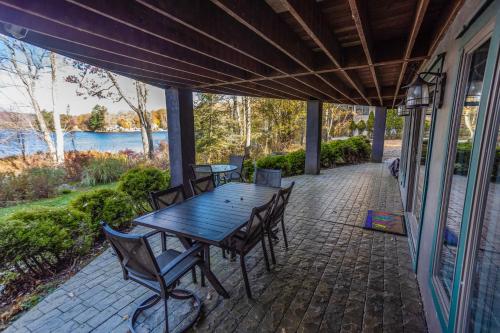 a table and chairs on a patio with a view of the water at Lakefront, Dock, Hottub, Pooltable, Kayaks, 75"tv in Lake Ariel