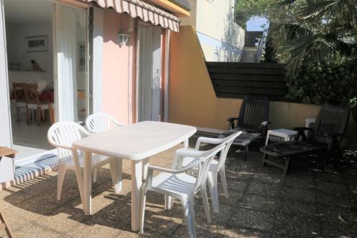 une table blanche et des chaises sur une terrasse dans l'établissement Appart 801, Tennis village, au Cap d'Agde