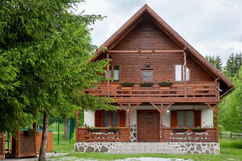 a wooden house with flowers on the balcony at Kamilla Vendégház Borzont in Borzont