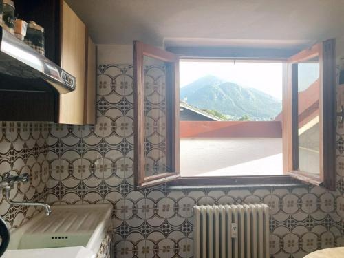 uma cozinha com uma janela com vista para uma montanha em Spacious mountain view attic apartment em Barzio