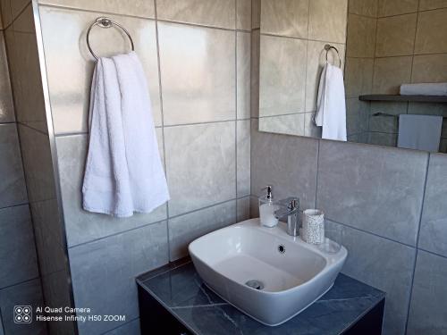 een badkamer met een witte wastafel en een spiegel bij Waterstone Park 1 Bed in Lombardy East