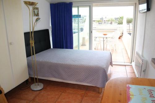 une chambre avec un lit et un balcon avec une table dans l'établissement Studio 19, Héliopolis FGH au Village naturiste, au Cap d'Agde