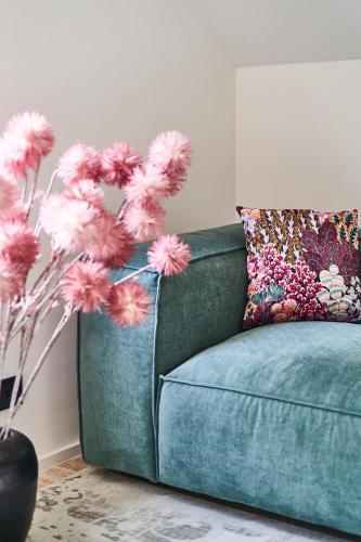 a blue couch with a pillow and pink flowers at PRIMERA am See in Gaienhofen