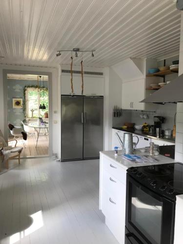 a kitchen with a stainless steel refrigerator and white cabinets at Rum på hästgård in Holmsjö