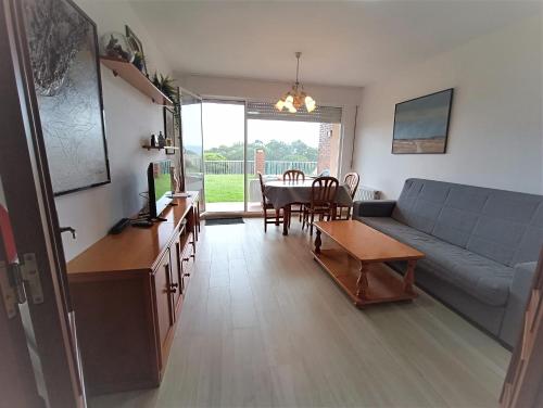 uma sala de estar com um sofá e uma mesa em Apartamento con jardin privado junto playa Usil - Mogro em Miengo