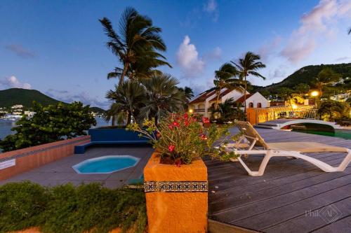 a deck with a pool and a chair and flowers at CasaPisani Tranquil 2Bed condo SimpsonBayYachtClub in Simpson Bay