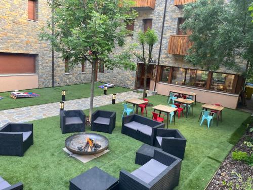 un patio al aire libre con una hoguera, mesas y sillas en Hotel Els Encantats, en Espot