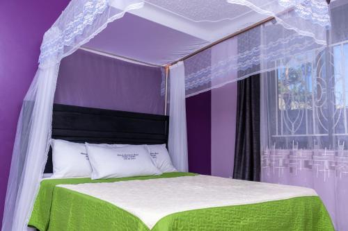 Cama en habitación púrpura con dosel en Kinene Residence Motel Entebbe en Nalugala
