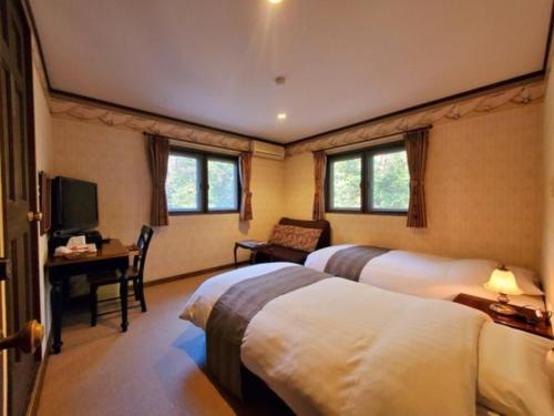a hotel room with two beds and a desk and a television at Gusthof Lumiere - Vacation STAY 41349v in Fujikawaguchiko