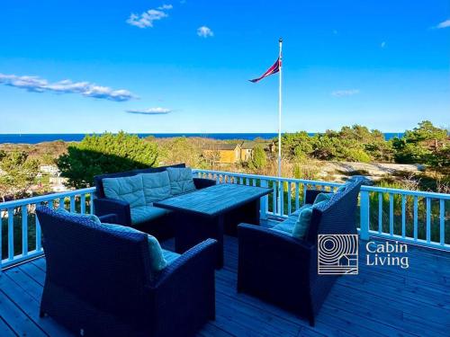 a deck with blue chairs and a table and a flag at Southern cottage with terrace and magnificent view in Lillesand
