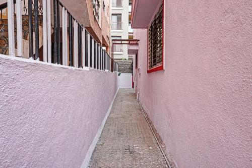 Lohogaon的住宿－OYO Flagship 87488 Hotel Green Breeze，一座狭窄的小巷,在一座建筑旁边设有粉红色的墙壁