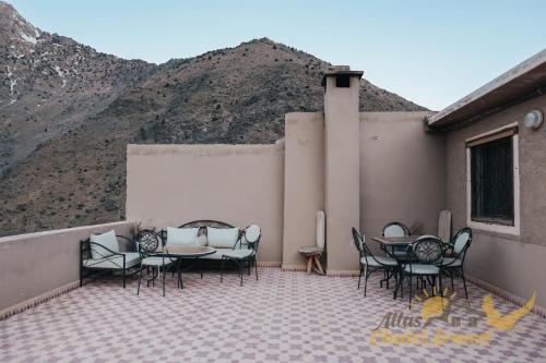 a patio with tables and chairs and a mountain at Atlas Chalet Armed in Imlil