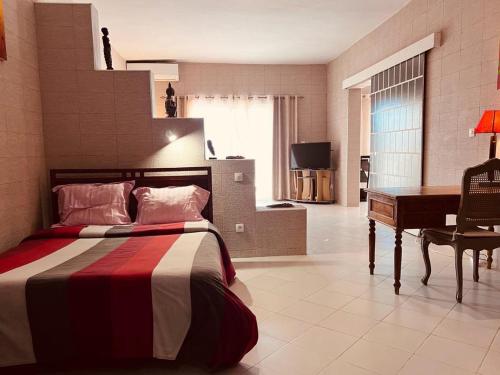 a bedroom with a bed and a desk and a piano at F2 Meublé au VIRAGE in Ngor