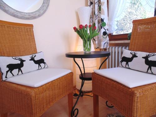 two chairs with black deer cushions and a table with flowers at Allgäu Sonne in Oberstdorf