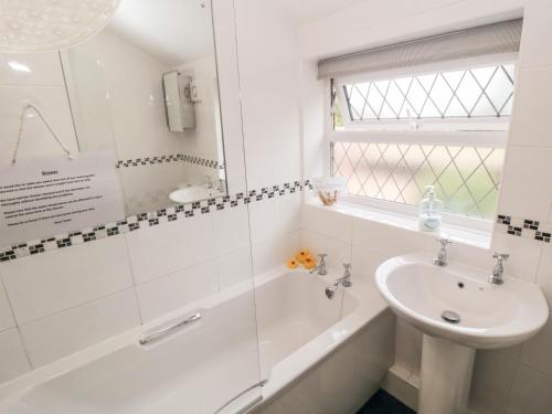a white bathroom with a sink and a tub and a shower at Sunnyside Cottage in Filey