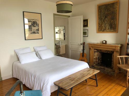a bedroom with a white bed and a fireplace at La Chambre de L'Embarcadère in Le Conquet