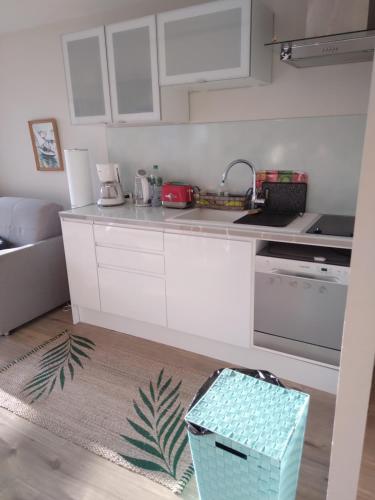 une cuisine avec des armoires blanches et une boîte bleue sur le sol dans l'établissement Magnifique appartement double cabine, à Le Touquet-Paris-Plage