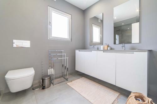 ein Badezimmer mit Toilette, Waschbecken und Spiegel in der Unterkunft Villa Kamila in Aroeira