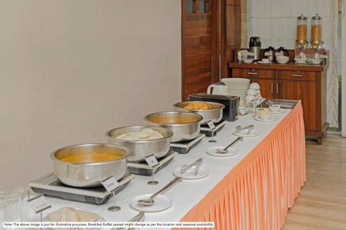 a table with several pots and pans of food at Treebo Down Town, Dalhousie in Dalhousie