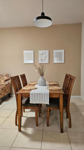 a dining room table with four chairs and a vase on it at Departamento Frontera #4 en el Campestre in Ciudad Juárez