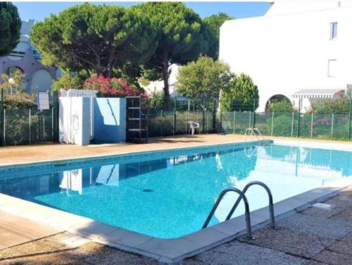 une piscine avec de l'eau bleue dans une cour dans l'établissement Magnifique studio avec loggia, au Grau-du-Roi