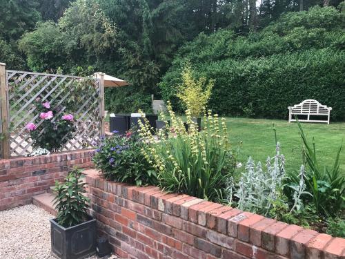 a garden with a brick retaining wall and flowers at The Cheese Room, self-contained cosy retreat in the Quantock Hills in Bridgwater