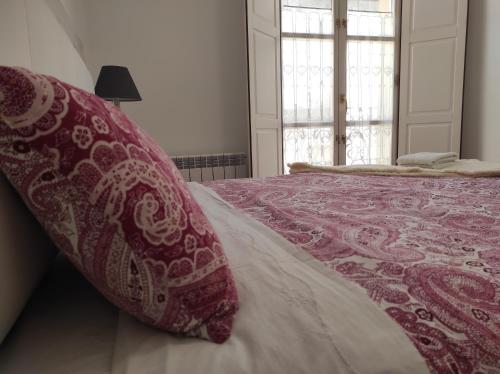a bed with a red and white blanket and a window at EL CAPRICHO DE BACO in Haro