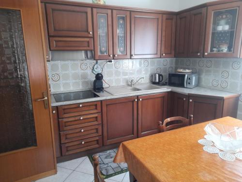 uma cozinha com armários de madeira, um lavatório e uma mesa em Casa vacanze Gianluca em Aosta