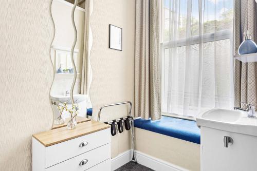 a bathroom with a mirror and a sink and a window at The Netley in Torquay