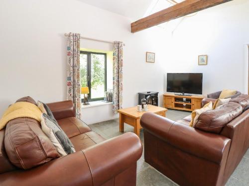 a living room with two leather couches and a tv at The Long Barn in Attlebridge