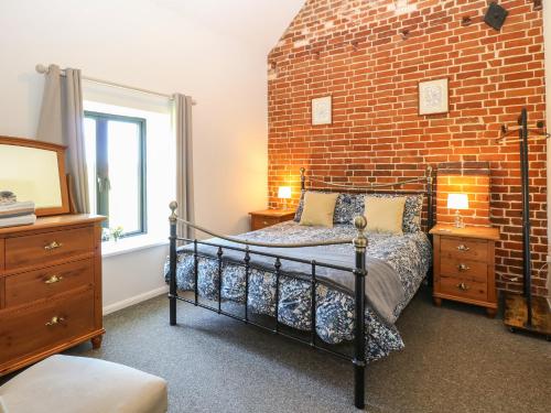 um quarto com uma parede de tijolos e uma cama em The Long Barn em Attlebridge