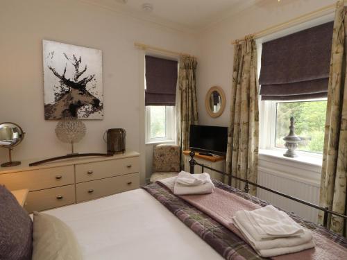 a bedroom with a bed and a tv and windows at North Lodge in Annan