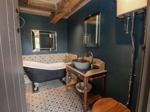 a bathroom with a tub and a sink at The Tractor Shed in Preesgreen